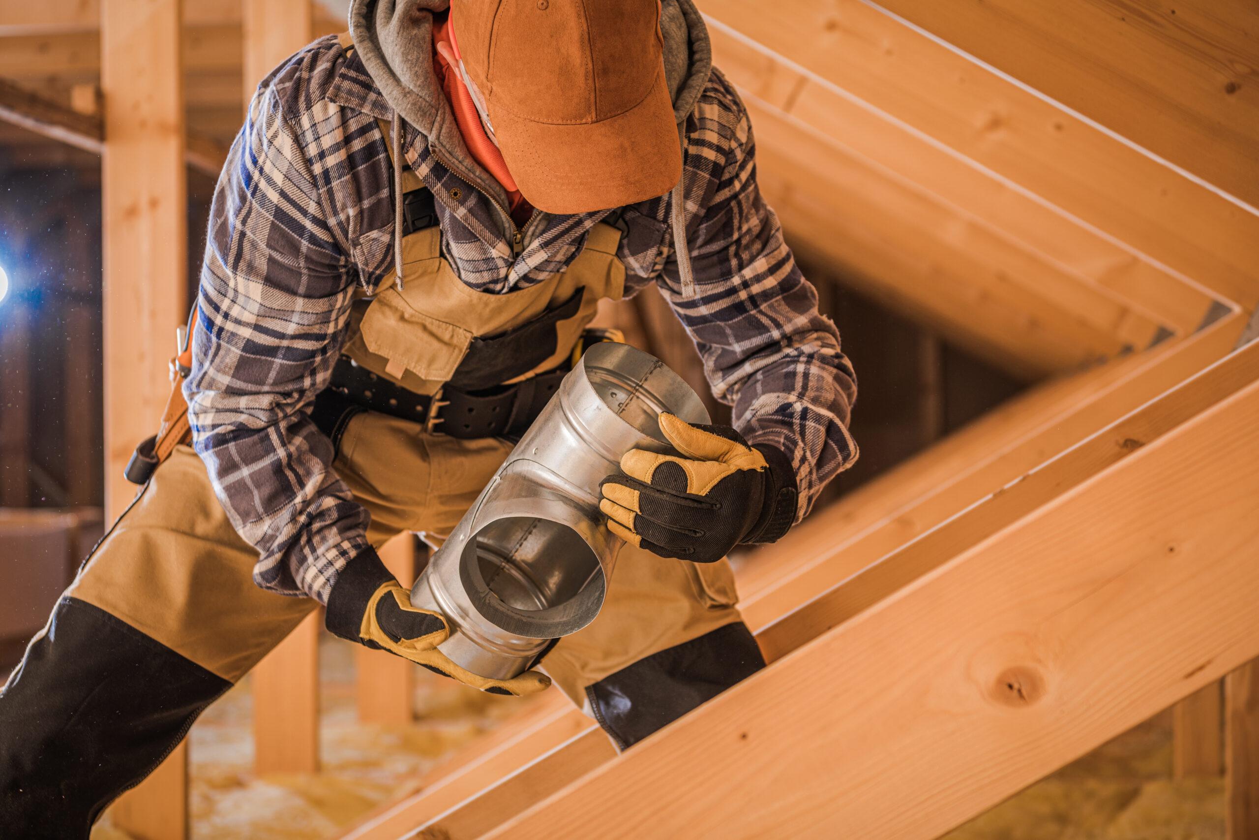 Male Contractor Assembling HVAC Pipes In Attic Of New House.
