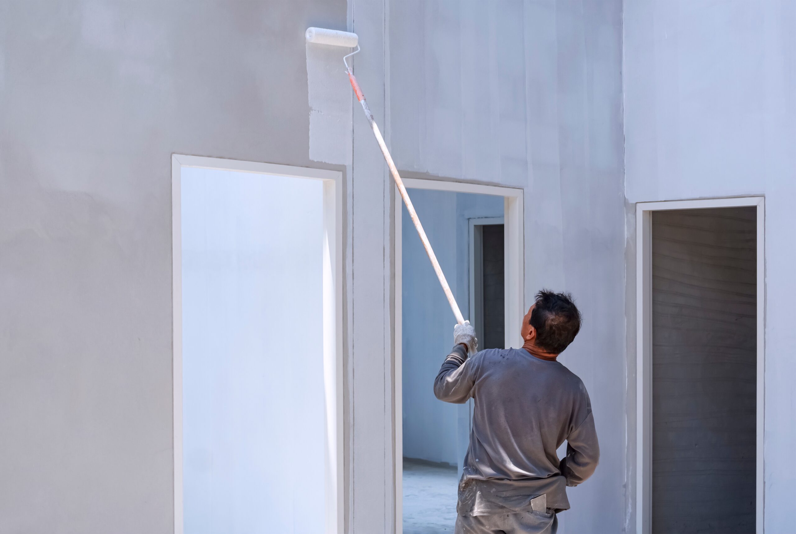 Worker painting wall with paint roller