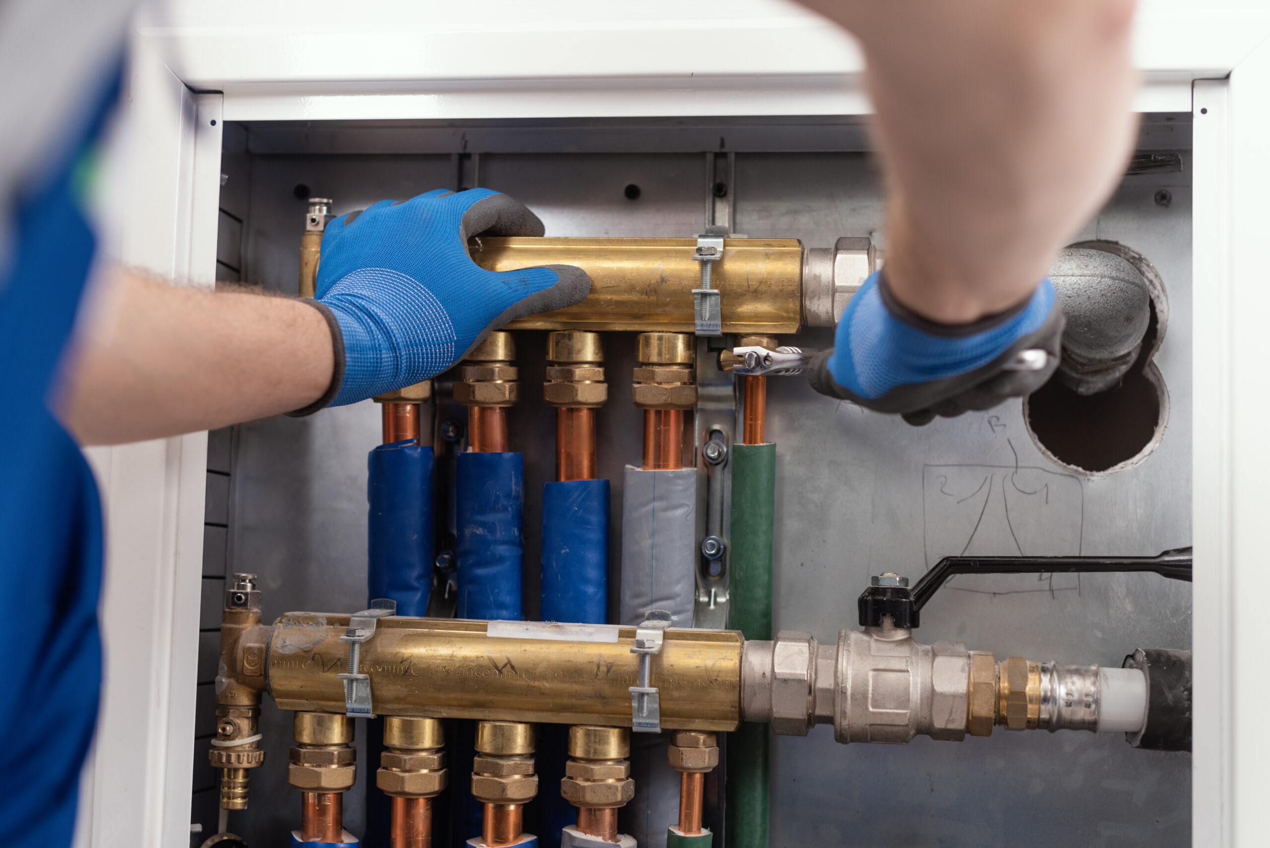 Professional plumber installing plumbing manifolds at home, home improvement and repair concept